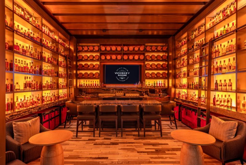 Surrounded by bottles of exclusive whiskeys and rows of barrels, the intimate Whiskey Room is bathed in golden light.