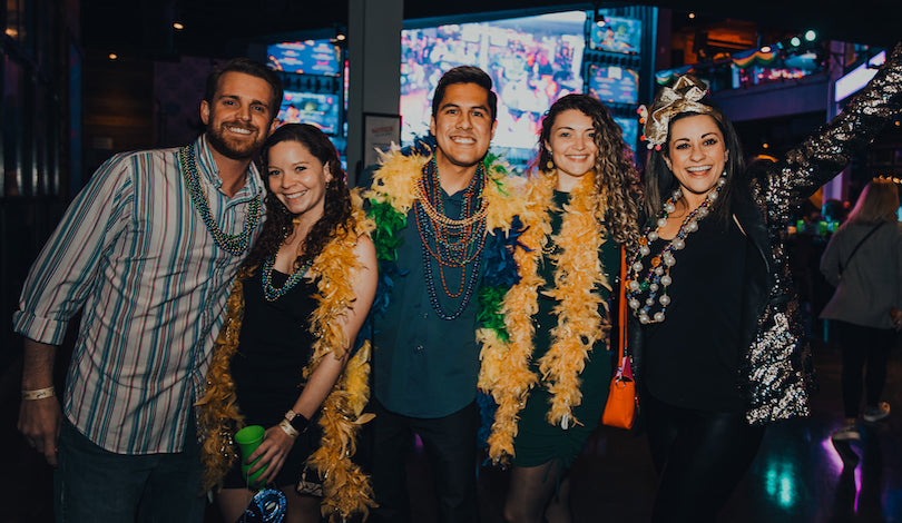 Five friends (two men and three women) are dressed for Mardi Gras success, complete with beads, boas and big smiles!