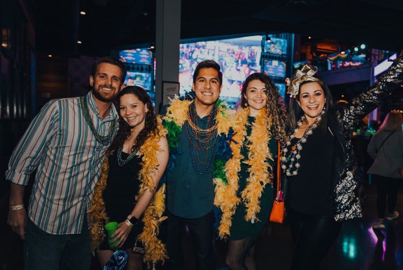 Five friends (two men and three women) are dressed for Mardi Gras success, complete with beads, boas and big smiles!