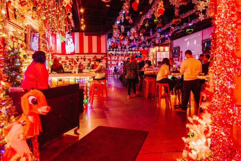 Bar and dining area decorated for the holidays with tinsel and garland hanging from the ceiling, Christmas tree, Santa, and Rudolph the Red Nosed Reindeer.