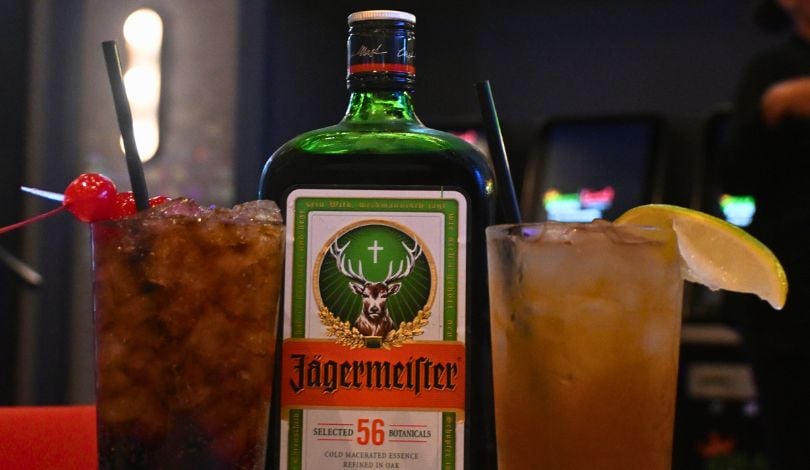 image of two jagermeister cocktails in collins glasses with a jagermeister bottle in the middle