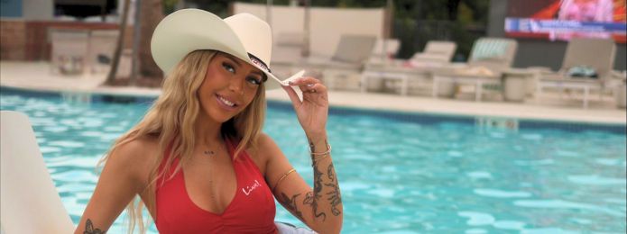 image of a blonde girl sitting by the pool with a cowboy hat on