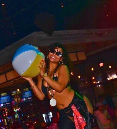 image of a girl holding a beach ball and wearing sunglasses at pbr cowboy bar