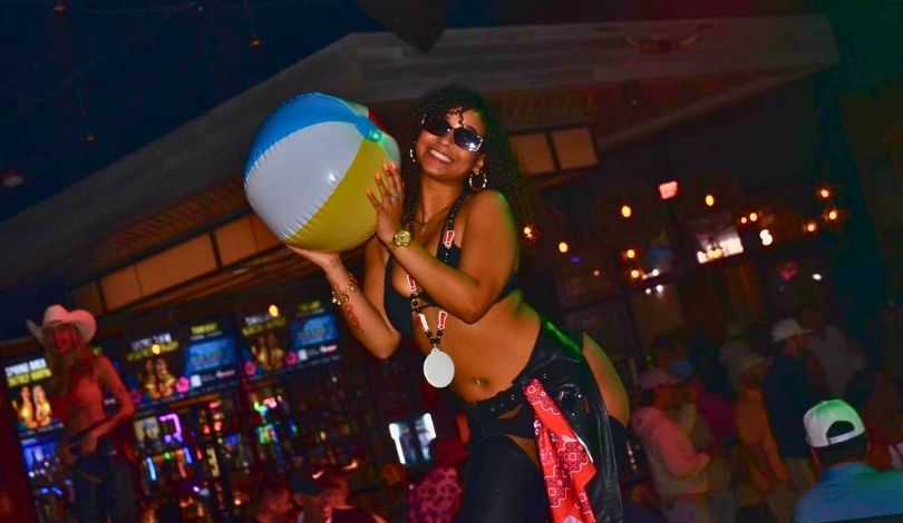 image of a girl holding a beach ball and wearing sunglasses at pbr cowboy bar