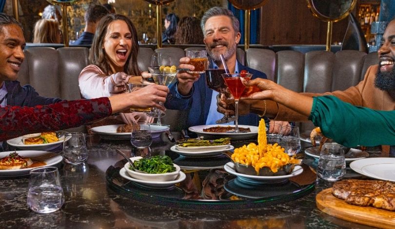image of people clinking glasses together over dinner at the prime rib