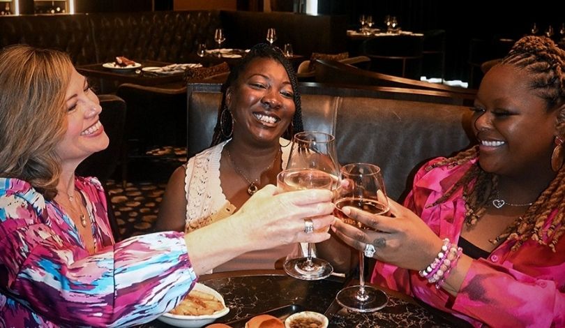 image of three women clinking glasses together at the prime rib