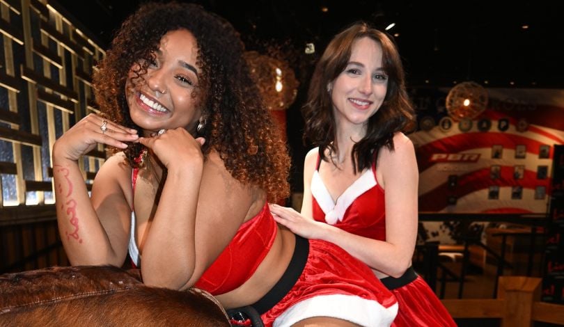 image of two girls wearing santa outfits sitting on a mechanical bull at pbr louisiana