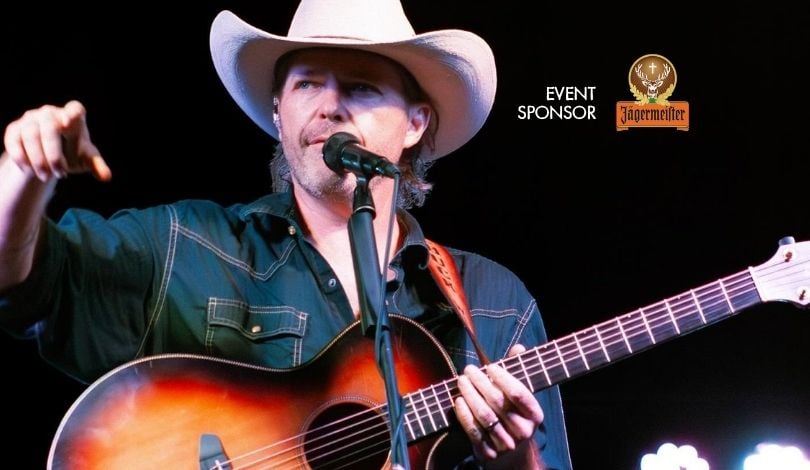 image of chuck wimer band lead singer holding a guitar and singing into a mic on stage