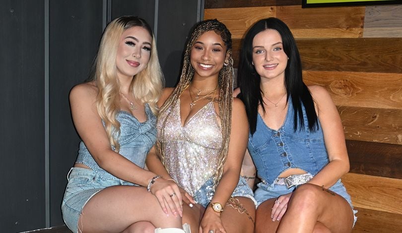 image of 3 girls sitting on a coach wearing denim, diamonds, and cowboy boots