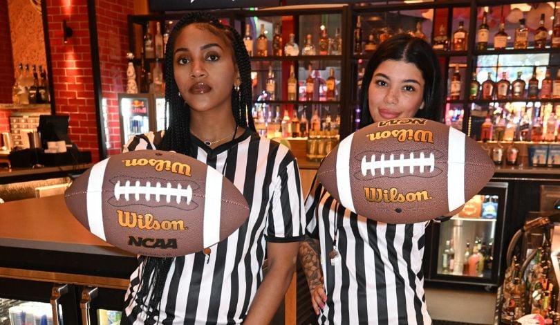 image of two girls holding footballs with referee shirts