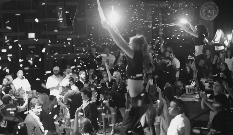 black and white image of the midnight blackout at PBR - buckle bunnies on boxes dancing and throwing confetti and holding sparklers - people dancing in a crowded room