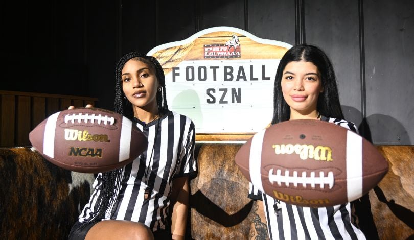 image of two girls with referee shirts on holding footballs to promote football season at pbr louisiana