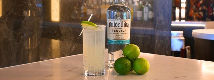 image of a margarita in a tall glass sitting beside limes and a dulce vida tequila bottle