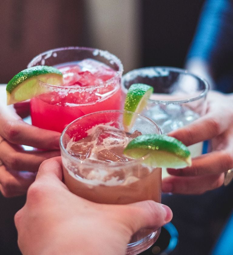 image of three people holding margarita glasses with lime garnishes