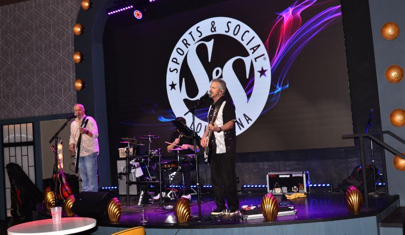 image of 3 men on stage at sports & social louisiana playing instruments