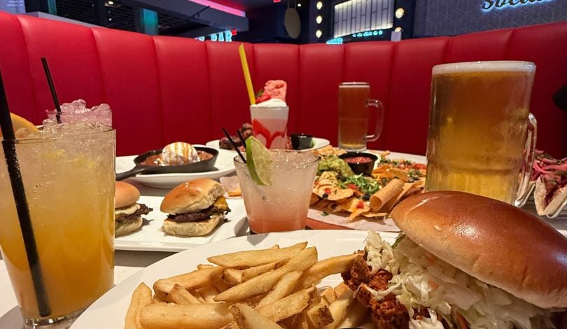 image of table of food at sports & social louisiana including cocktails, chicken sandwich, beer, milkshakes, sliders, cookie skillet, nachos, and tacos