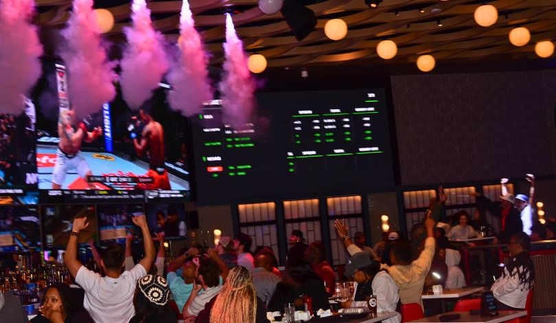 image of crowd of people in sports & social louisiana watching the UFC fight on the 110 ft media wall cheering with smoke coming from ceiling