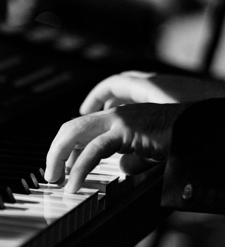 black and white image of hands playing piano keys