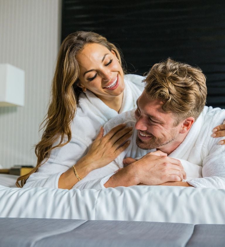 Young couple on a bed enjoying the room and laughing