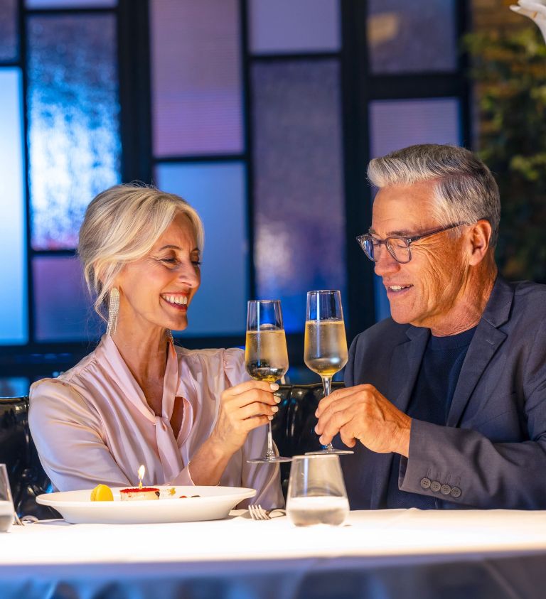 Older couple at a nice restaurant, gazing at each other, enjoying some white wine together