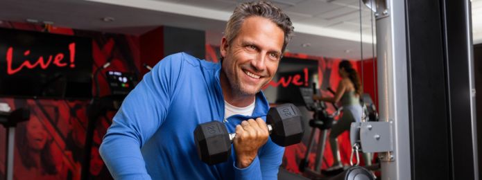 man curling a dumbbell in a gym 