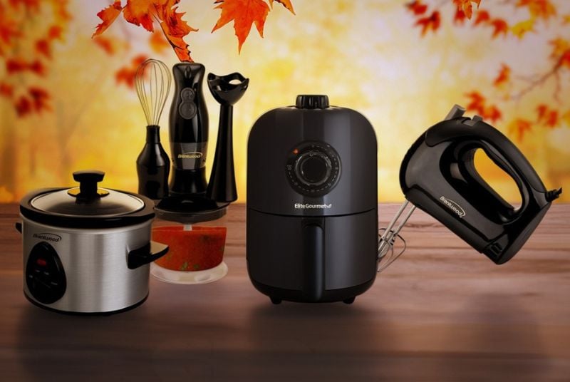 A crockpot, immersion blender, air fryer, and hand mixer on a fall background.