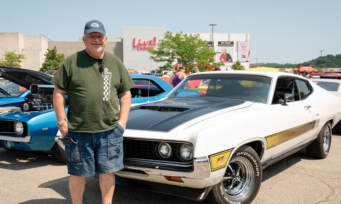 car cruise guest standing next to a muscle car