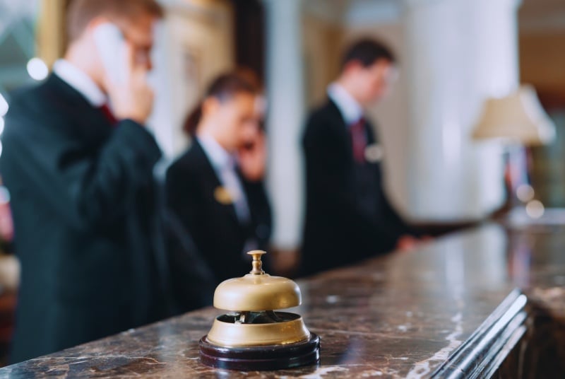 image of a check in desk at a hotel with three agents and a concierge bell