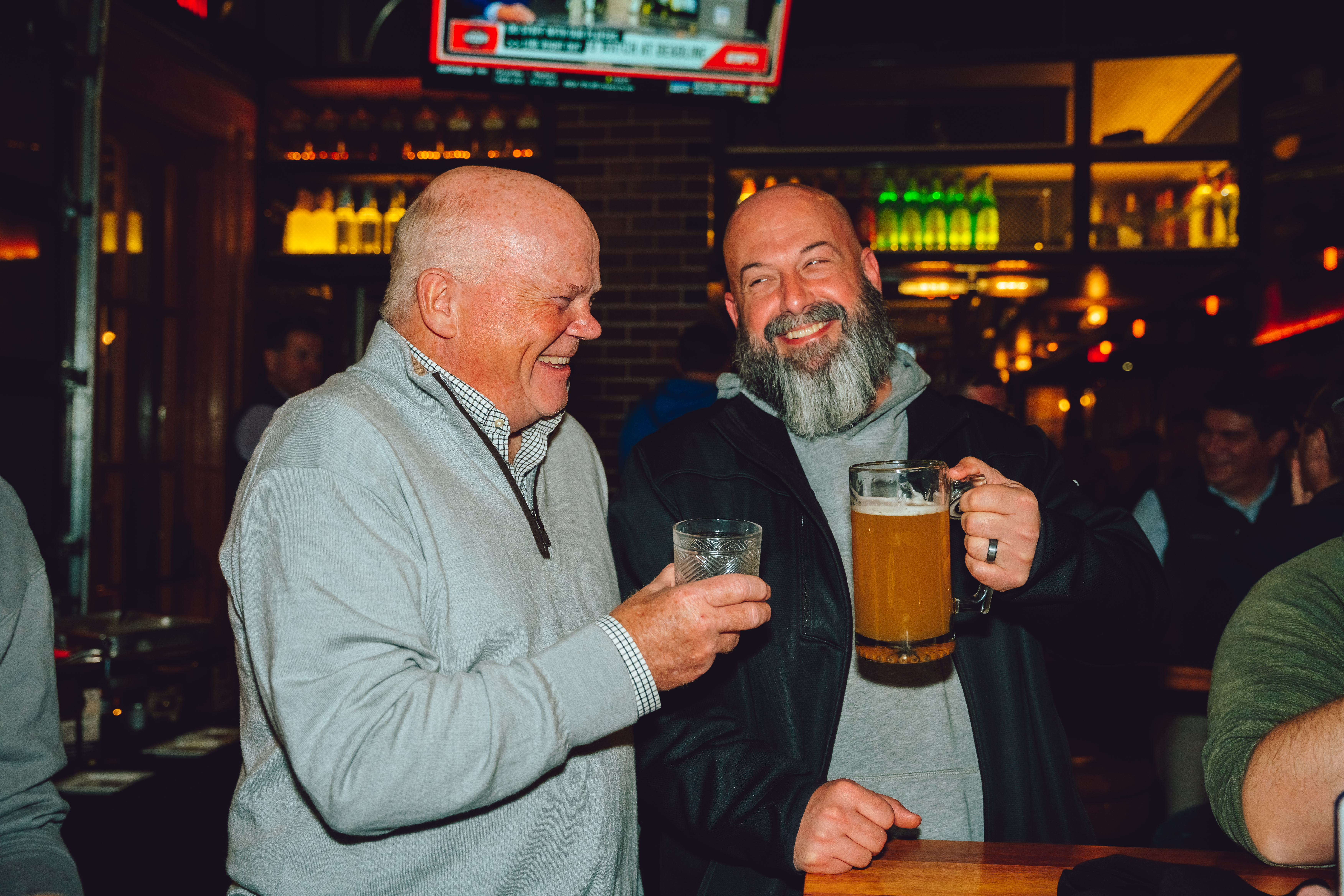 Two men laughing and smiling at happy hour at Guy Fieri's Smokehouse