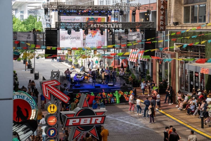 A band plays on a festive Cinco de Mayo stage at 4th St Live as audience members dance and look on.