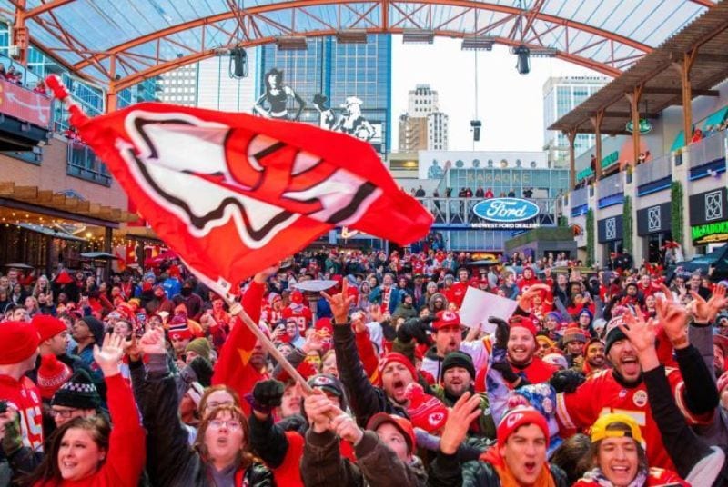 A passionate crowd cheers and a fan waves a Kansas City Chiefs flag in celebration of the team's AFC win at Kansas City Live!