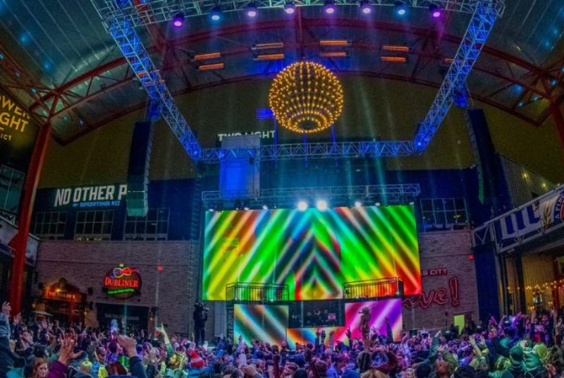 Flanked by brightly-colored screens, a DJ revs up a dancing New Year's Eve crowd at Kansas City Live!