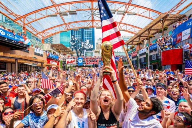 A woman holds up a replica of the FIFA World Cup trophy as the crowd around her cheers the US women's soccer team's victory!