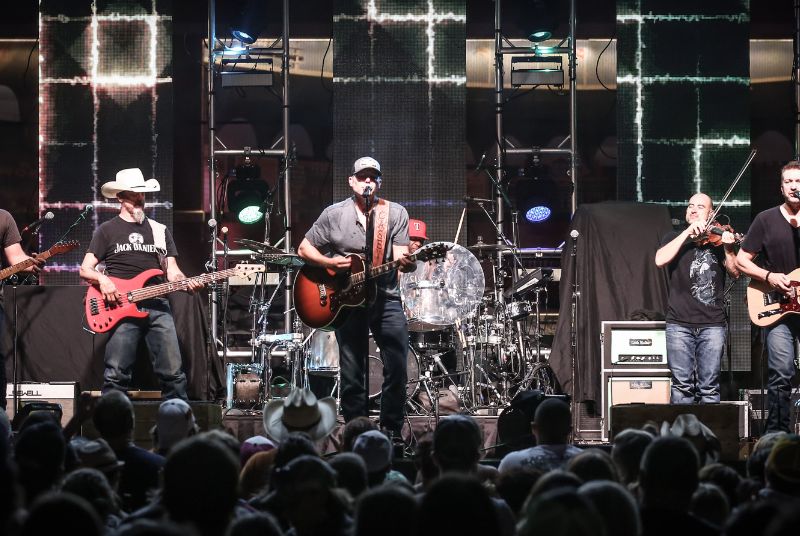 The Downtown Hoedown crowd watches as a band performs, featuring three guitarists, a bassist, a drummer and a violinist.