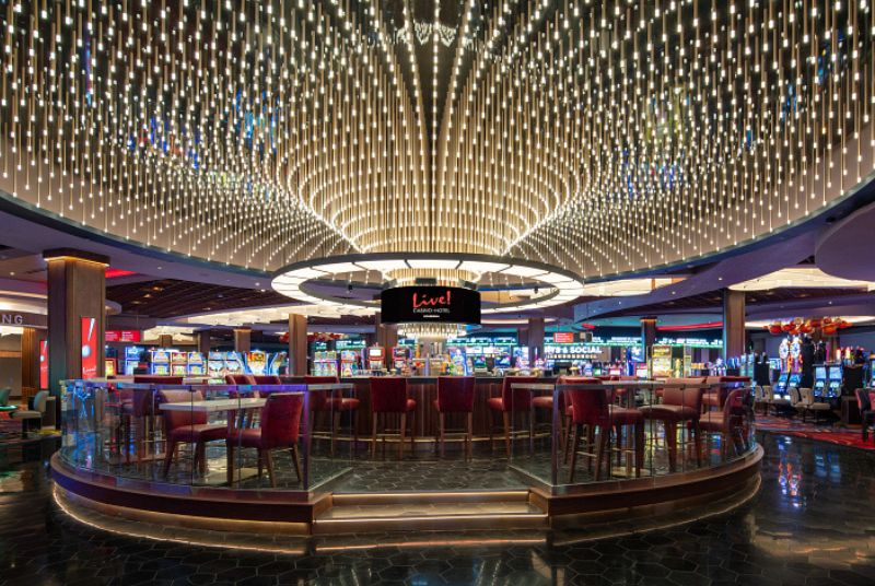 Circular bar area with bar seating and colorful lights above. In the middle of the casino floor surrounded by slot machines.