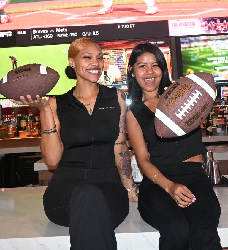image of two girls who work at sports & social louisiana holding footballs to promote football game day watch parties