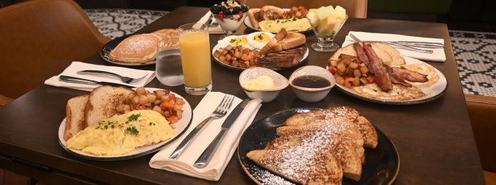 Breakfast foods such as french toast, bacon, eggs, and orange juice on the table at Ridotto Grand Cafe. 