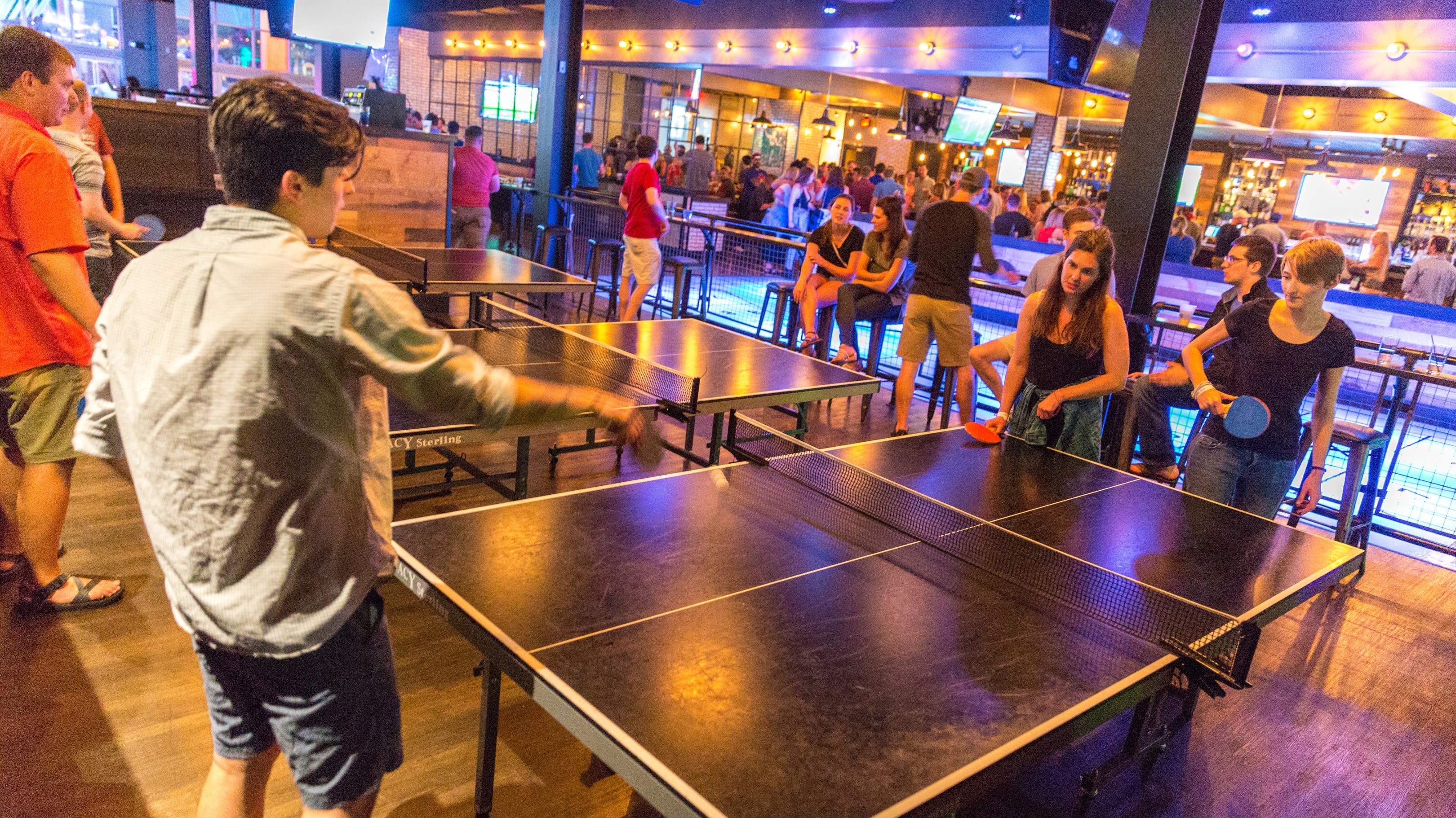 People playing ping pong at an upscale bar.