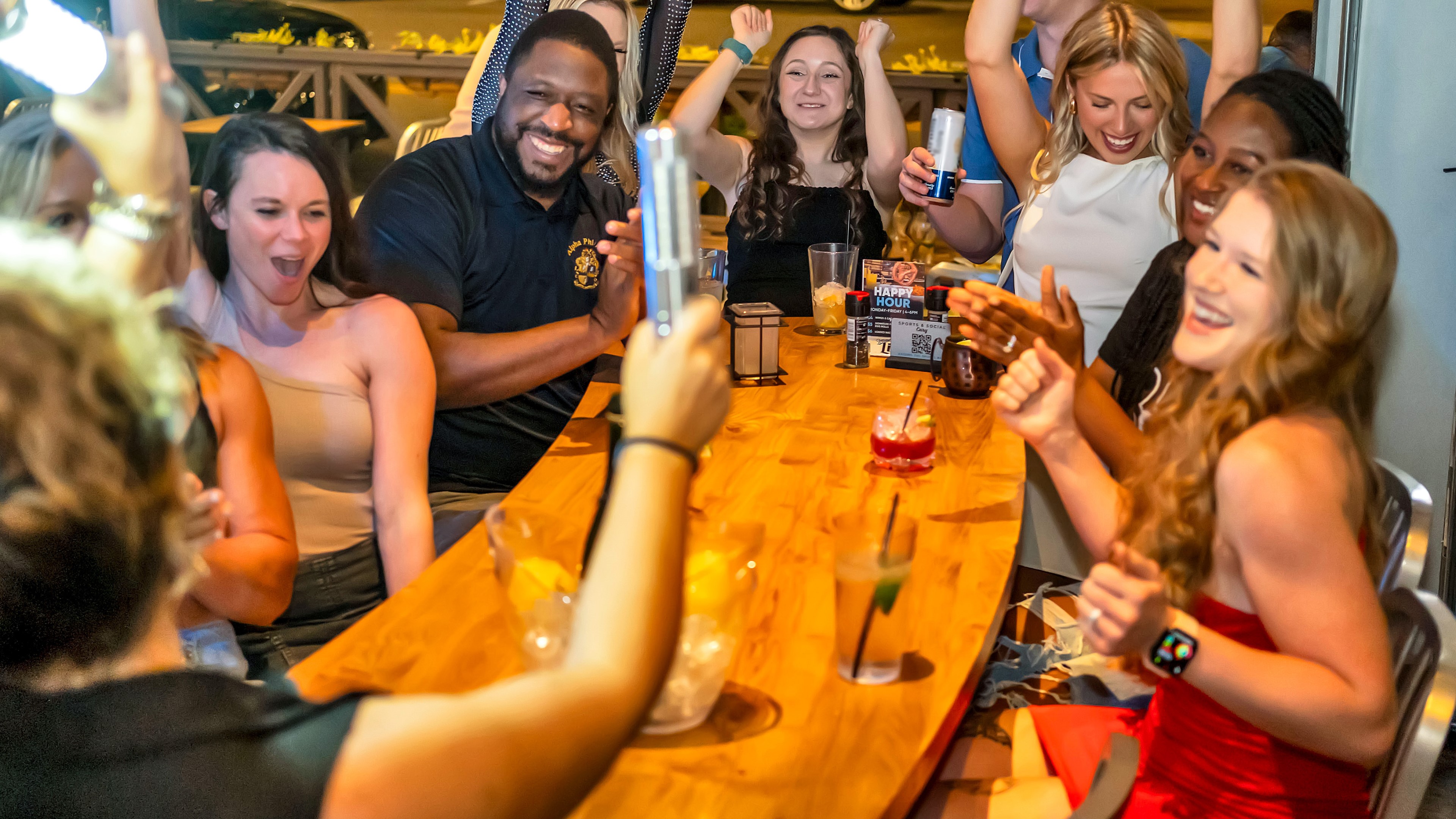 Server with party lights at table with lively group.