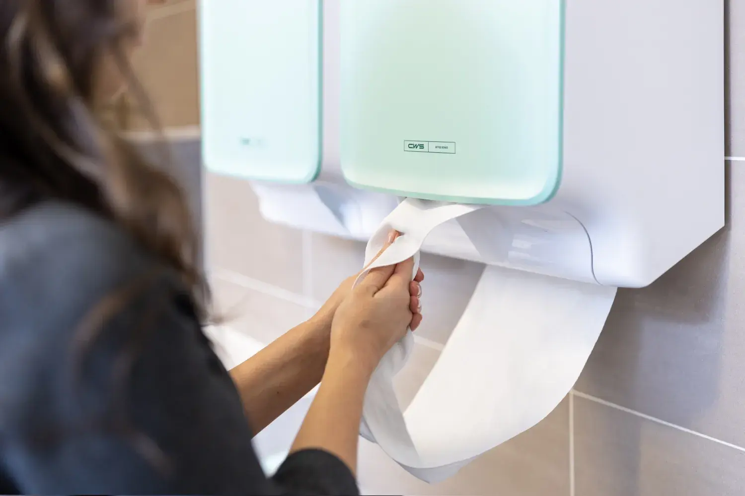 Woman drying her hand on a CWS Cotton Towel dispenser