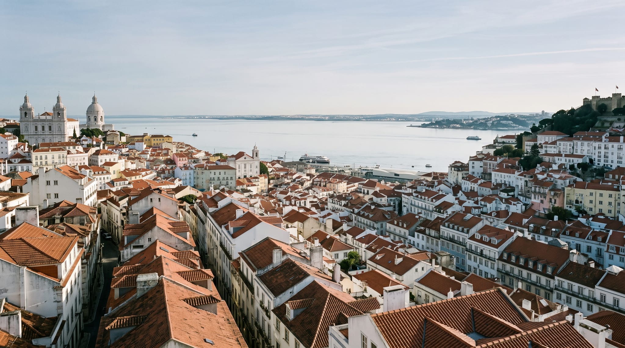 Lisbon rooftops stepping down to the Tagus estuary in clear morning light