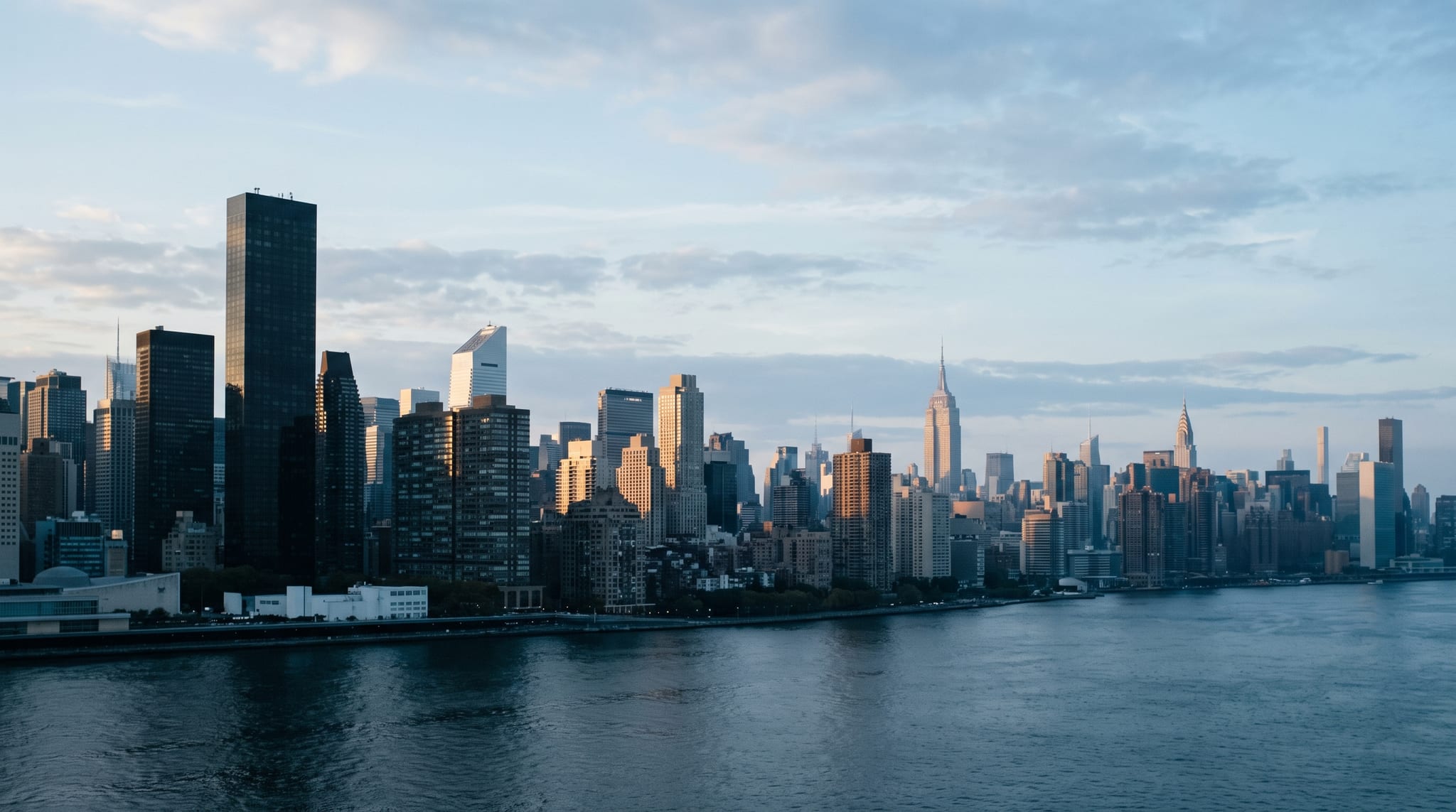 The Manhattan skyline in low evening light across flat water