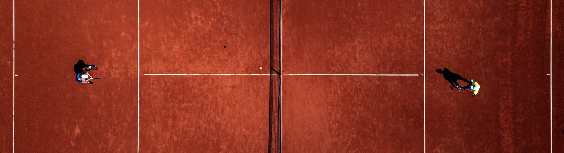 Top_view_of_two_people_playing_recreational_tennis_on_a_clay_court_PPT