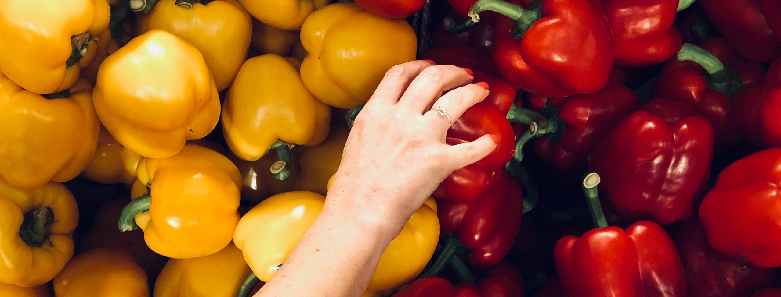 Hand reaching for vegetables and bell peppers