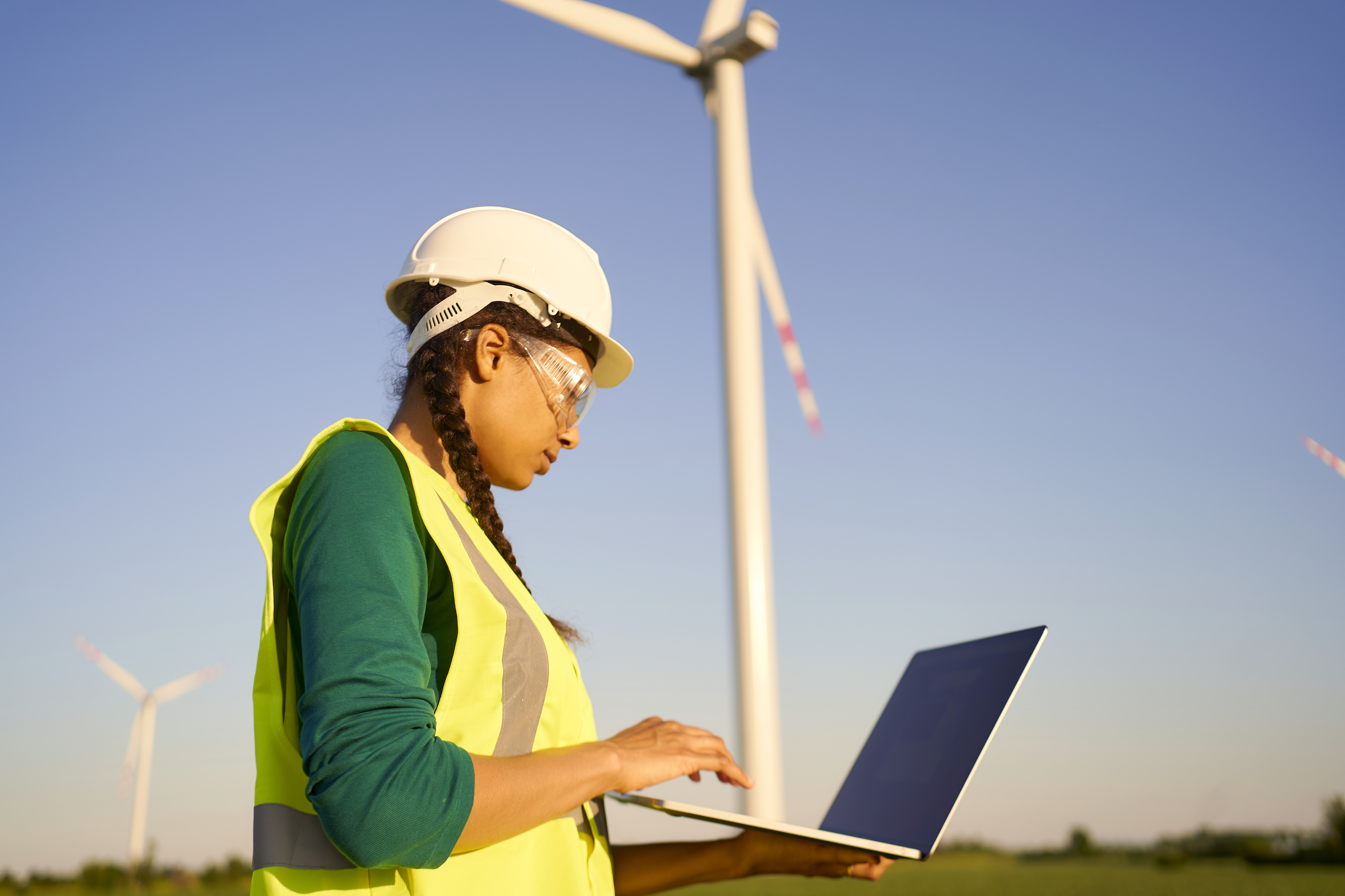 Engineer using a laptop near wind turbine