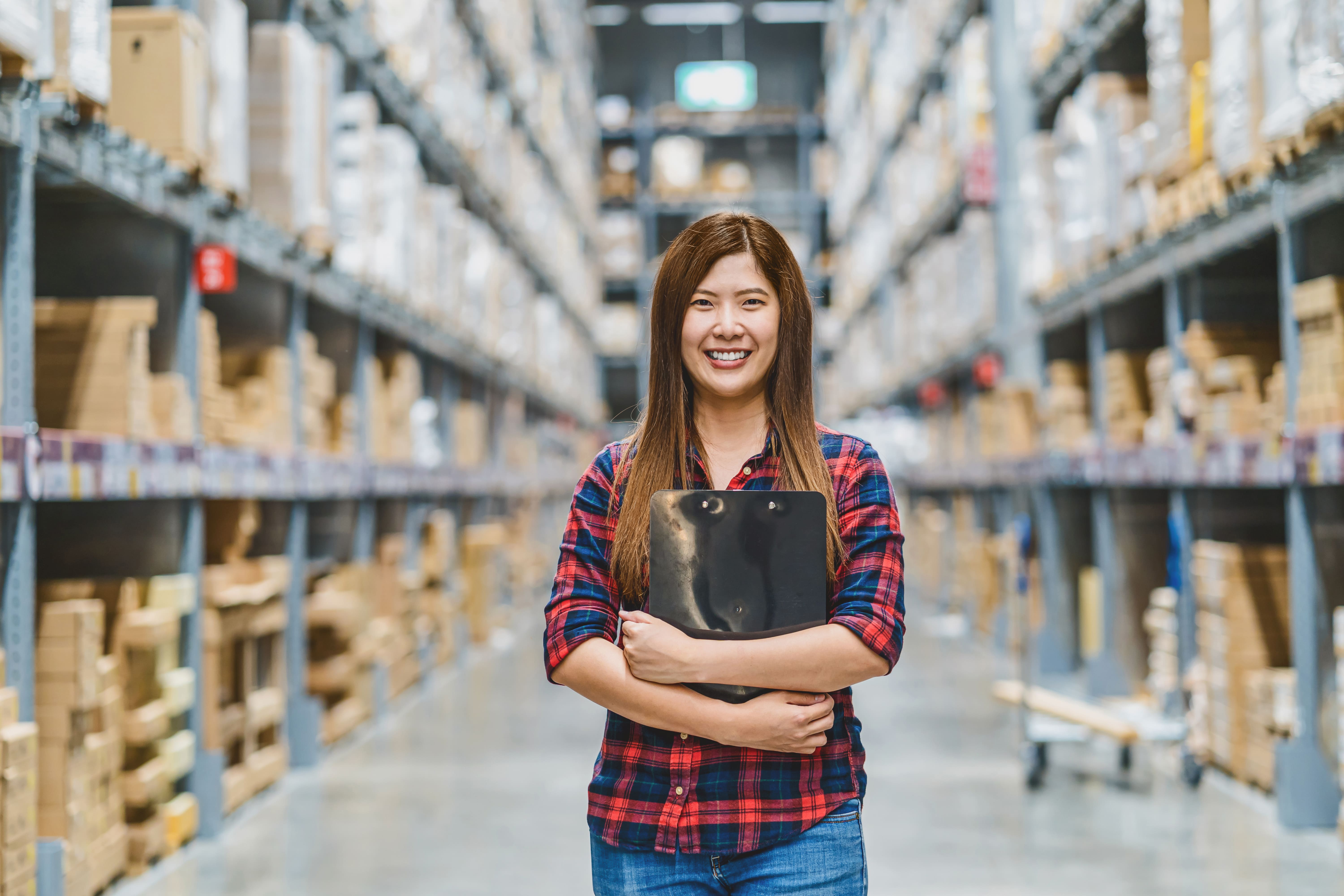 Woman in warehouse image - woman in warehouse holding clipboard