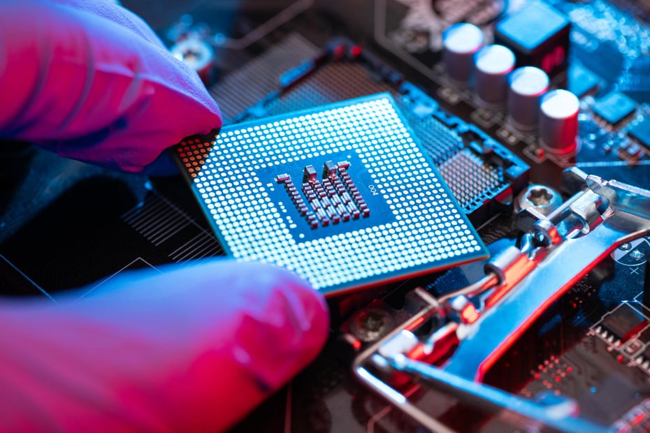 Technician installing a microprocessor on a motherboard with gloves, representing secure and high-performance logistics support for electronics manufacturing.