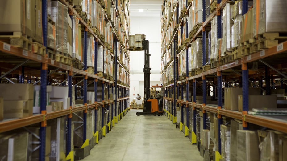 Forklift handling inventory inside a large distribution center, representing automated warehouse logistics and efficient inventory management systems.