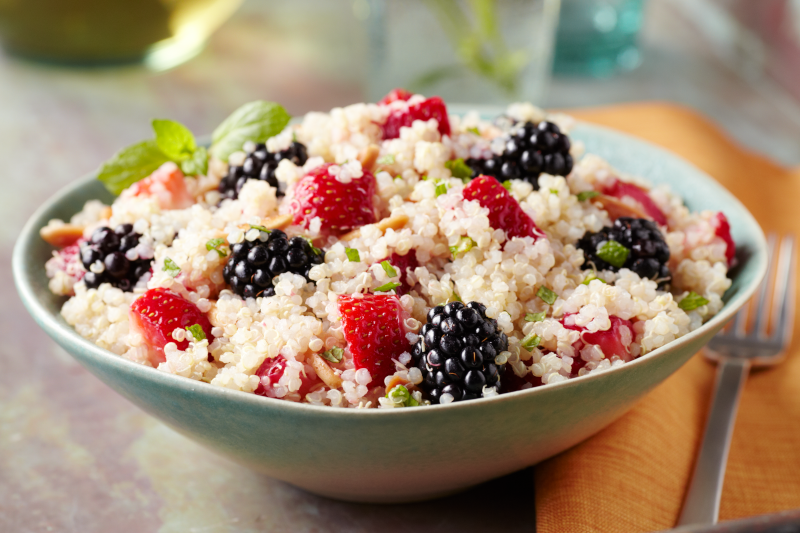 Fluffy quinoa mixed with juicy strawberries and blackberries sit in a blue-gray bowl.