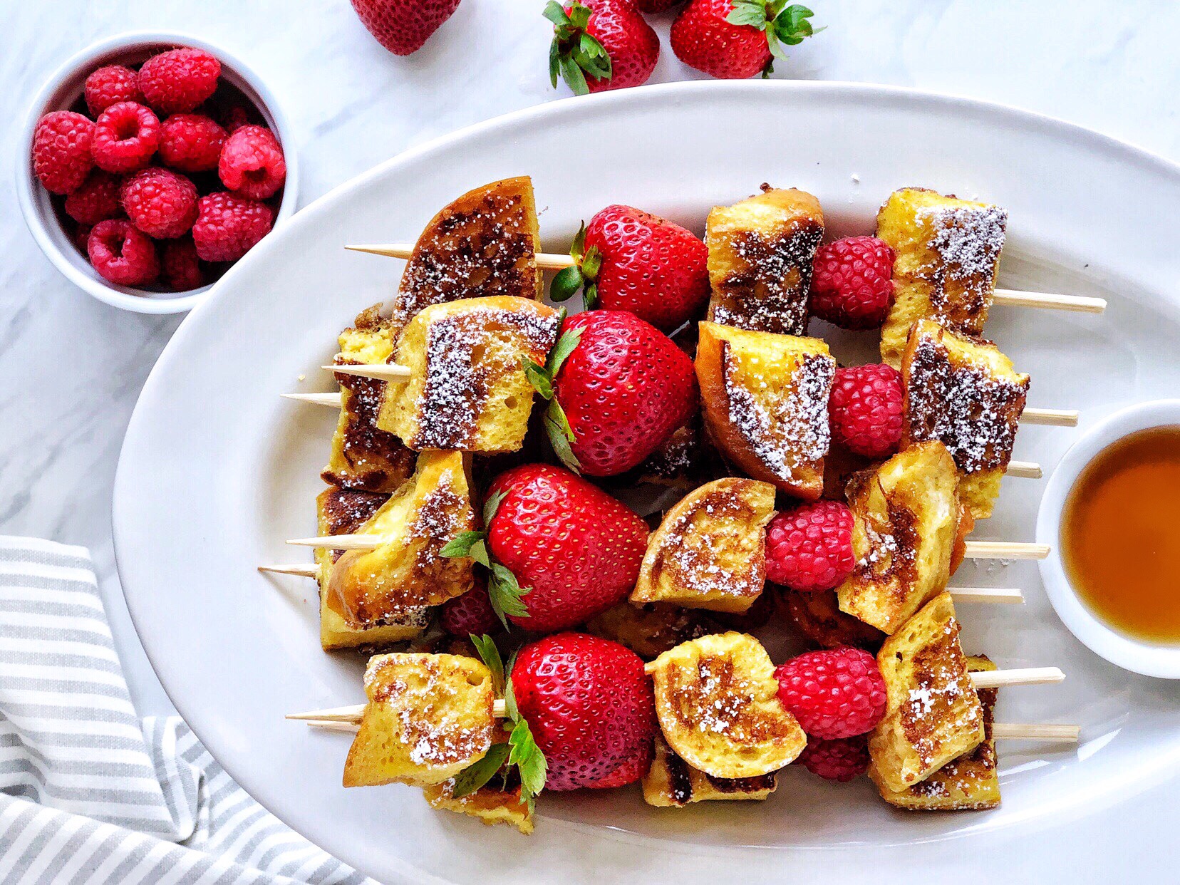 Berry french toast kebabs with french toast pieces, raspberries, and strawberries on a skewer